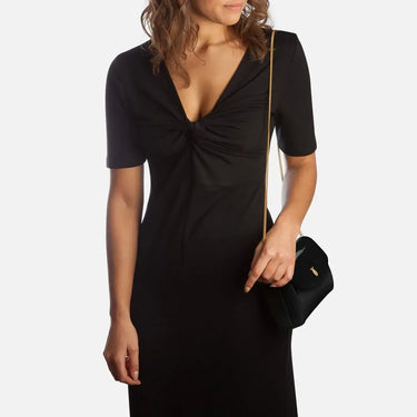 Woman wearing a black dress holding a black handbag on a white background