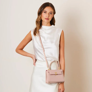 Woman holding a pink handbag against a plain background