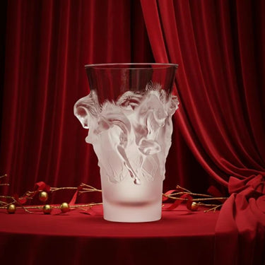 Decorative glass vase with artistic design on a red surface with red curtains in the background. The vase takes centre stage. 