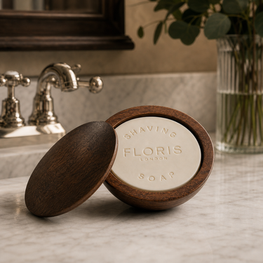Floris Shaving soap in a wooden dish on a bathroom counter.