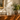 Clear glass vase with intricate design on a wooden surface, with a framed painting in the background.